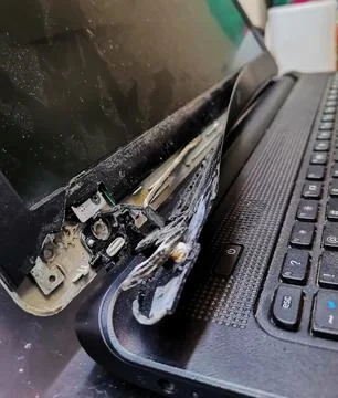 A macro side view of a severely damaged laptop computer showing a broken hinge Stock Photos