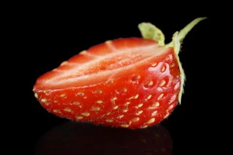 Macro side view of single half of strawberry isolated on black background Stock Photos