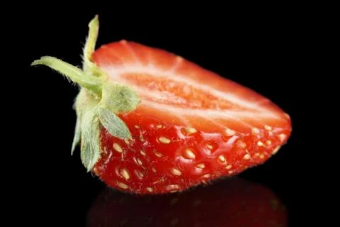 Macro side view of single half of strawberry isolated on black background Stock Photos
