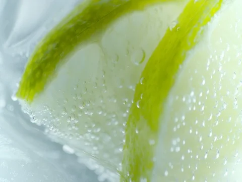Macro of a slice of lime in a drink covered with bubbles  Stock Footage 76675520