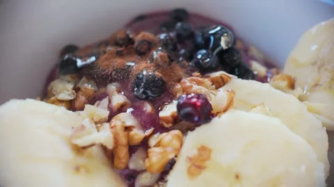 Macro slow motion cinnamon sprinkle over oatmeal with fruit and nuts, aroma.. Stock Footage 329844359