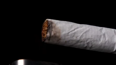 Macro slow-motion lighting a cigarette with fire, isolated black background. Video stock 147075349
