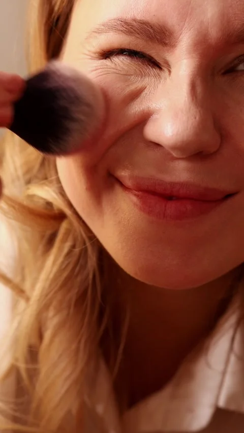 Macro of smiling woman applying blush with large makeup brush Stock Footage 329613259