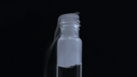 Macro smoke gently billows out of half full vial on black BG Stock Footage 70706239