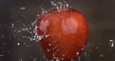 Macro of splashing water drops are falling on spinning bio organic red apple Video stock 269354766