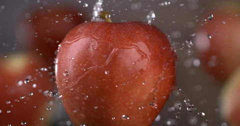 Macro of splashing water drops are falling on spinning bio organic red apple Stock-Footage 269354827