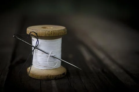Macro of a spool of white thread and a needle with black sewing thread Stock Photos