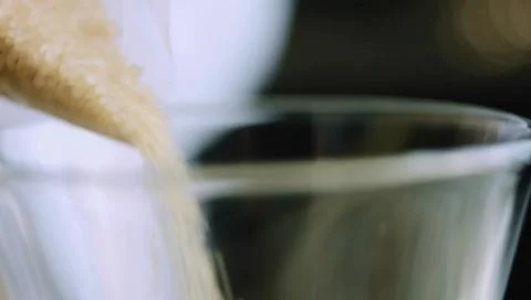 Macro Stream of Coarse Brown Sugar Falling into a Clear Measuring Glass Stock Photos