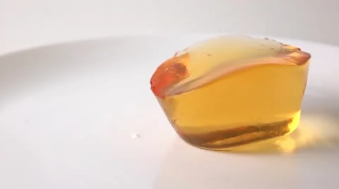 Macro super slow motion video of orange jelly falling on white plate Stock Footage 60228464