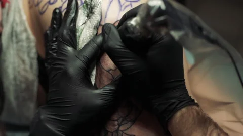 Macro tattoo master in gloves paints over girl thigh tattoo Stockbeeldmateriaal 104863874