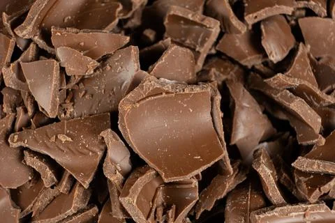 Macro texture of broken milk chocolate pieces pile background Stockfoto's