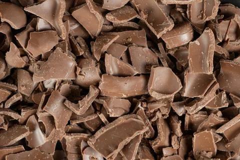 Macro texture of broken milk chocolate pieces pile background Stockfoto's
