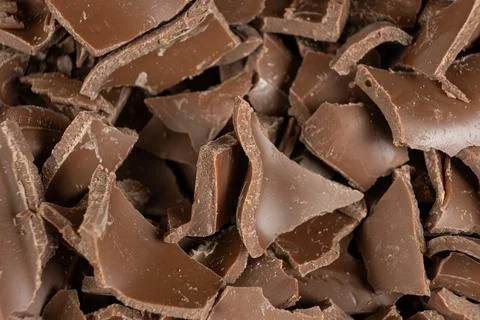 Macro texture of broken milk chocolate pieces pile background Fotos Stock
