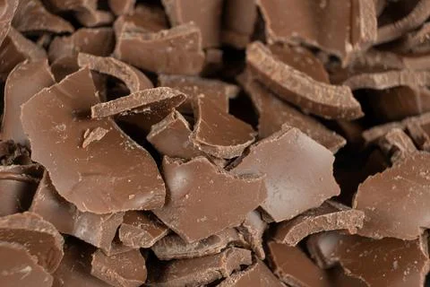 Macro texture of broken milk chocolate pieces pile background Stockfoto's
