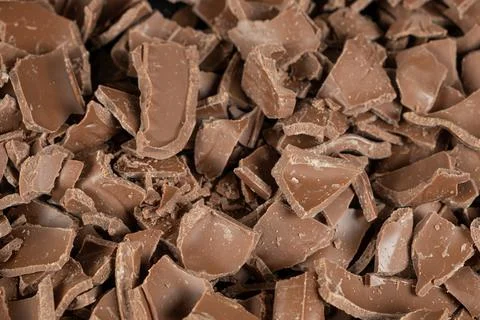 Macro texture of broken milk chocolate pieces pile background Stockfoto's