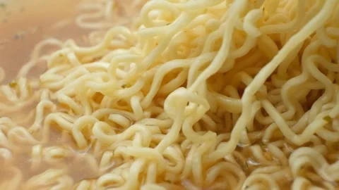 Macro texture of cooked instant ramen noodles floating in broth Stock Footage 346604626