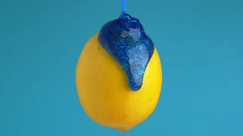 Macro texture shot of blue glitter flowing down a fresh lemon Stock Footage 230100032