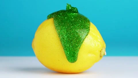 Macro texture shot of green glitter flowing down a fresh lemon on blue back.. Video stock 233888551