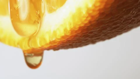 Macro Texture shot of Honey dripping down a fresh Orange slice on white Stock Footage 132585083