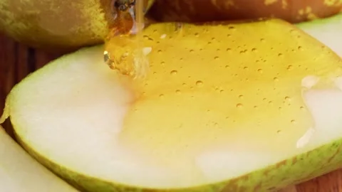 Macro texture shot of honey dripping down a fresh ripe yellow pears slice Stock Footage 231233429
