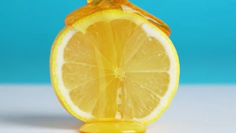 Macro texture shot of honey dripping down a fresh lemon slice on blue backg.. Stock Footage 233889726