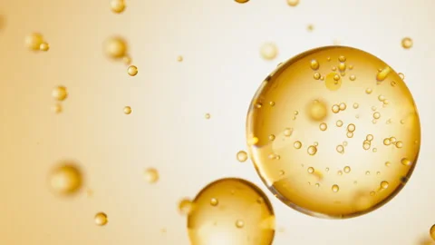 Macro of three drops of yellow liquid merge into one with bubbles inside. Skin Stock Footage 276735491