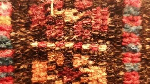 Macro tilt-down shot of a traditional hand-woven rug, showcasing intricate Vídeos de archivo 334108363