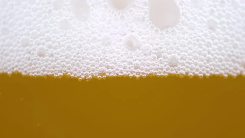 MACRO: Tiny bubbles form the foam on top of a glass full of pale ale beer. Stock Footage 166518025