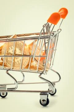 Macro tiny shopping trolley filled with shiny bitcoins Stock Photos