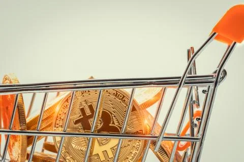 Macro tiny shopping trolley filled with shiny bitcoins Stock-Fotos
