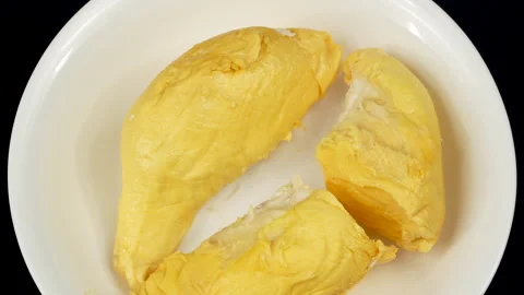 Macro top-down shot of bright yellow durian segments on a plate. Vídeo Stock 335083177