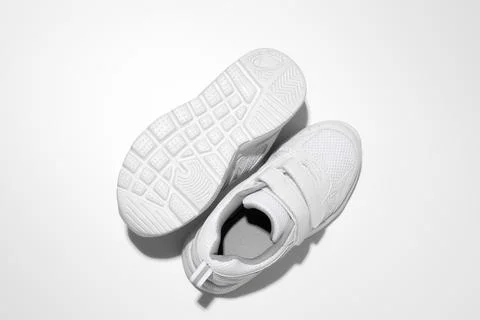 Macro top view Two white woman sneakers, one sneaker lies sole up with hard s Stock Photos