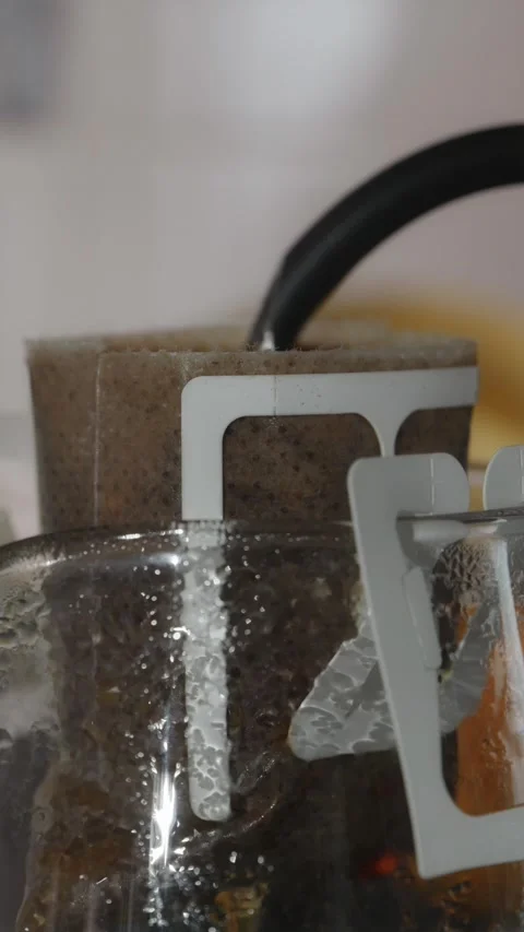 Macro vertical shot of hot water soaking coffee grounds in drip bag Stock Footage 338395205