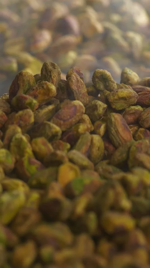 Macro vertical shot of shelled pistachio kernels being stirred with a wooden Stock Footage 334277060