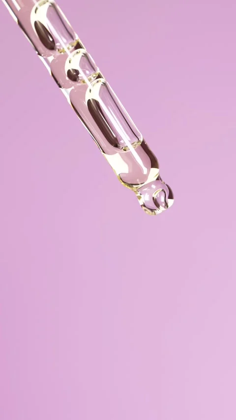 Macro vertical shot of yellow transparent oil or serum falling in slow moti.. Stock Footage 312763068