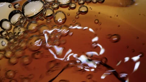 Macro video of dark amber liquid pouring with air bubbles and swirls Stock Footage 334604009