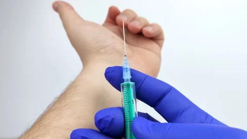 Macro video of a doctor’s hand with a syringe that draws blood from veins on the Stock Footage 125441981