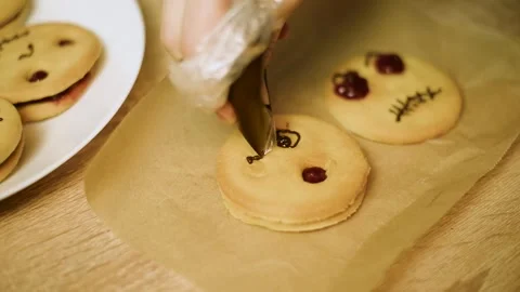 Macro video of drawing a spooky face on a shortbread cookie with chocolate Stock Footage 342704206