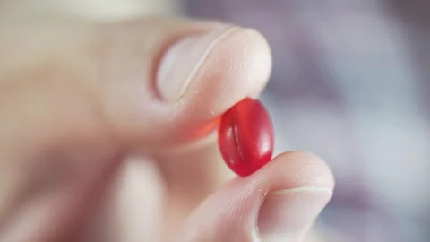 Macro video of fingers holding a red pill Stock Footage 278403241