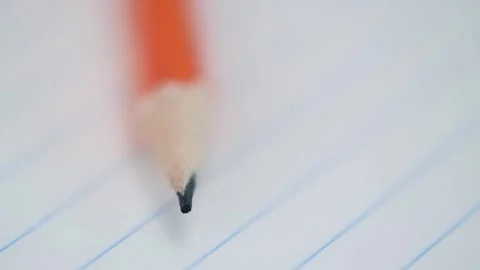 Macro video rotation of graphite pencil in closeup on empty sheet of an notebook Stock Footage 247401875