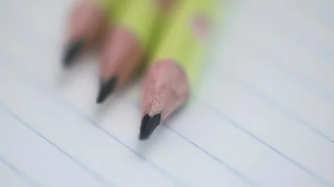 Macro video rotation of graphite pencils on sheet of an open notebook in ruler. Stock Footage 247492564