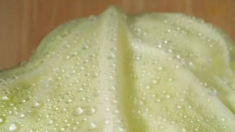 A macro video showcases a green cabbage glistening with droplets of water Stock Footage 244801197