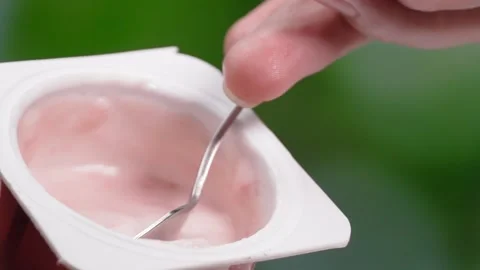 Macro videography, Slow motion yogurt with spoon in cup Stockbeeldmateriaal 248779172