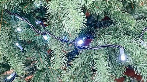 Macro view of artificial pine tree branches with glowing white holiday ligh.. Stock Photos