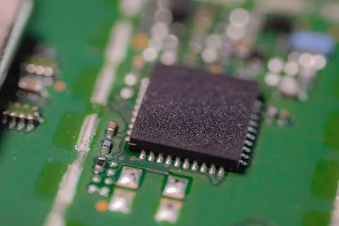 Macro view of black integrated circuit chip with fine pins on green printed.. Stock Photos