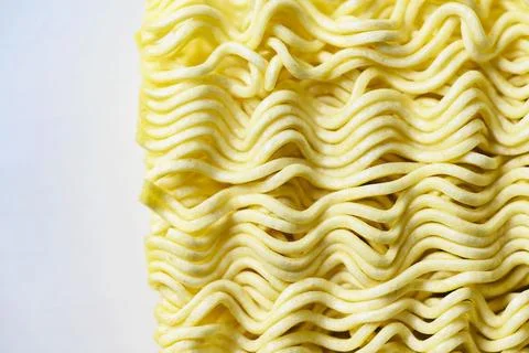 A macro view of a block of dry, yellow, wavy instant ramen noodles, showcas.. Stock Photos