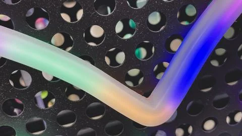 Macro view of a colorful gradient LED light tube against a black perforated.. Stock Photos