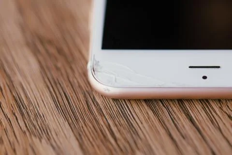 Macro view crack on the edge of the phone. Manicure. Wooden table in the cafe. Stock Photos