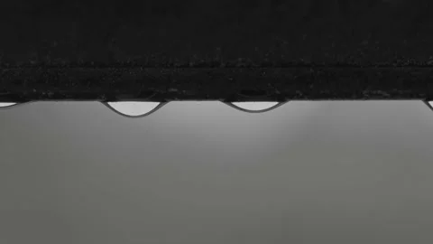Macro view of falling raindrops from  window frame of skylight during rain. Stock Footage 196732779