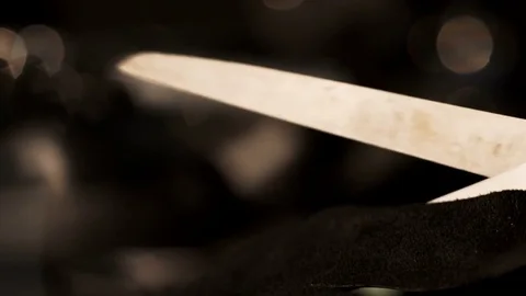 Macro view of female hand cutting black leather by metallic scissors while Stock Footage 77414025